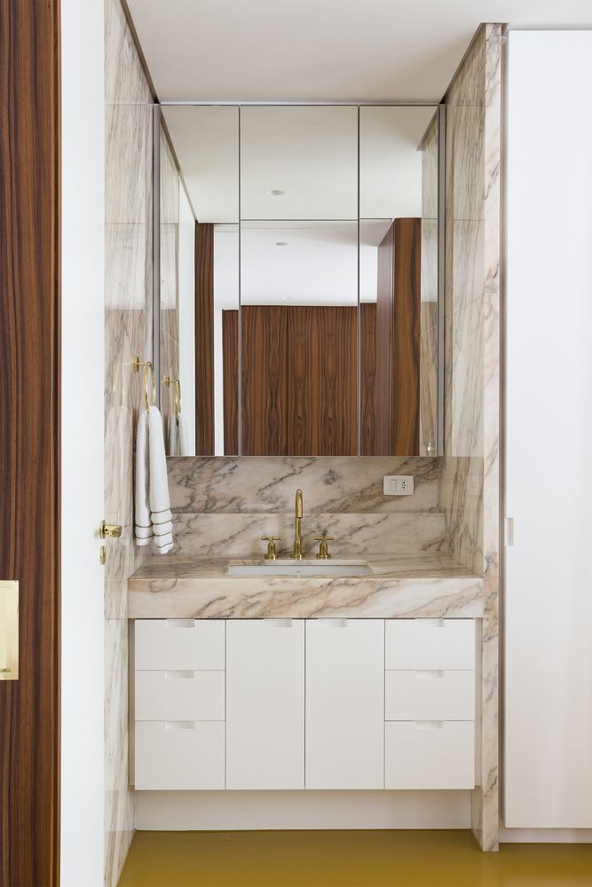 The bathroom is small but elegant, featuring marble and mirrored surfaces